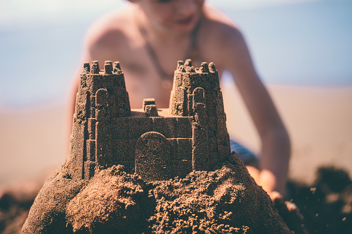 Boy and girl playing on the beach on summer holidays. Children building a sandcastle at the sea.