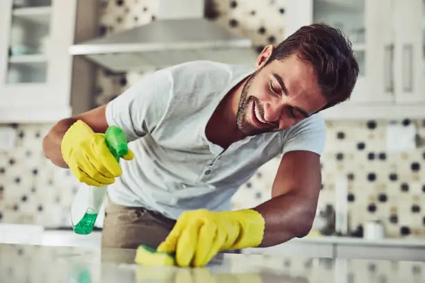Shot of a handsome young man cleaning his home