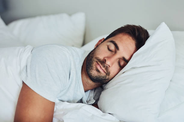 Some rest after a hard day's work Shot of a tired young man sleeping comfortably in his bed without a sign of being disturbed sleeping stock pictures, royalty-free photos & images
