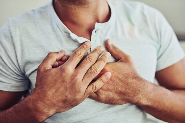 There's that chest pain again Shot of a unrecognisable young man holding his chest in discomfort with his hands due to pain in that area male chest pain stock pictures, royalty-free photos & images
