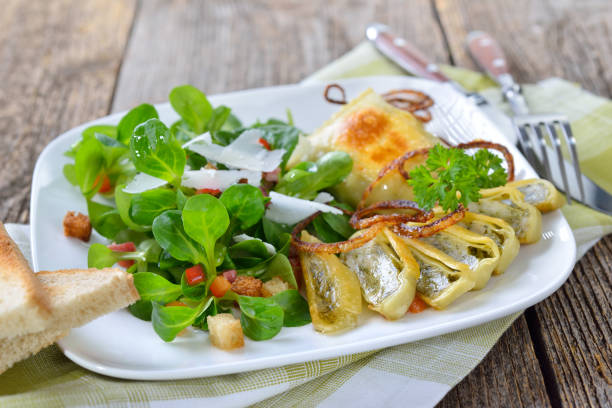 Fried Swabian meat ravioli (so called 'Maultaschen') served with corn salad with croutons, bacon and parmesan cheese