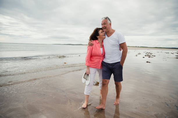 casal sênior caminhando na praia - beach shorts - fotografias e filmes do acervo