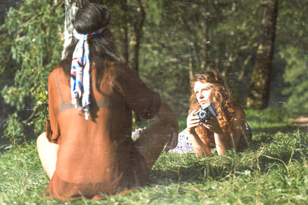 Pretty free hippie girls on the grass taking photos with an old - Vintage effect photo Pretty free hippie girls on the grass taking photos with an old camera. Outdoor in peace and free love. Top view - Vintage effect photo hippie photos stock pictures, royalty-free photos & images