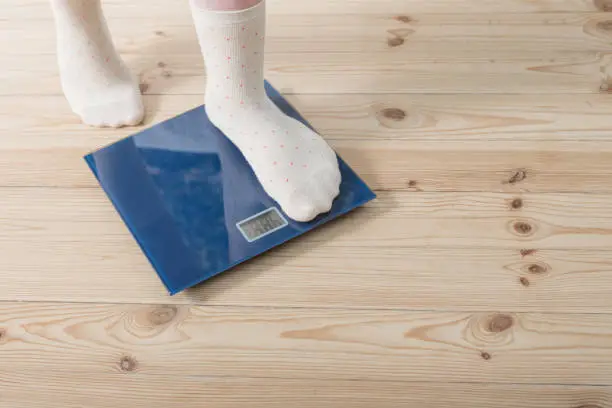 Photo of female feet in socks on the floor scales