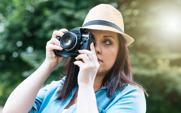 istock Portrait of pretty young woman using a camera, light effect 904169572