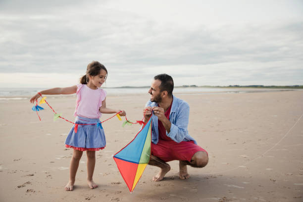 istock Father and Daughter Playing On The Beach With a Kite 904169960