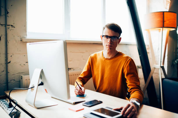 istock Portrait of handsome businessman working on new project in office analyzing information, skilled IT developer installing application on digital tablet sitting near computer looking at camera 904171228