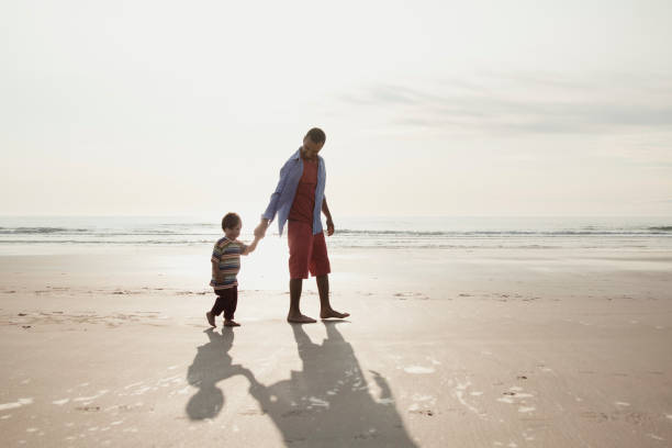 Boy with his father walking on the beach by the sea
