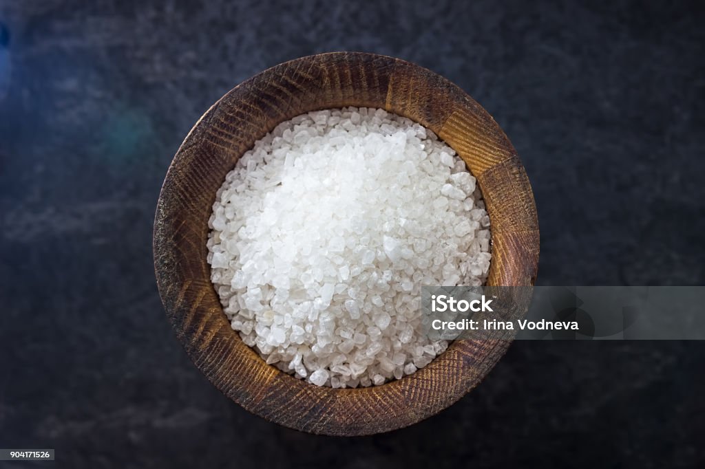Sea salt in a wooden salt shaker on black background. Ingredients for cooking. Sea salt in a wooden salt shaker on black background. Ingredients for cooking. Kitchen Ingredients. Salt - Seasoning Stock Photo