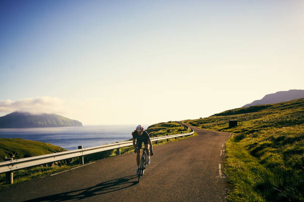 Shot of a young woman cycling on a long, winding road in the mountains