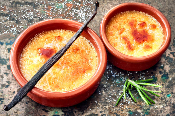 istock Creme brulee (cream brulee, burnt cream) with vanilla stick in terracota baking dishes 904178768