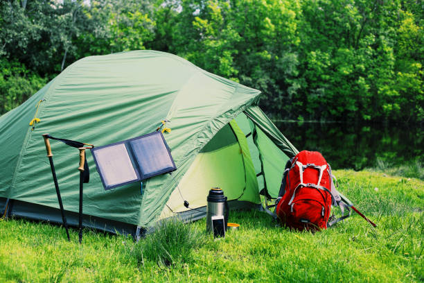 istock Camping on the river bank. The solar panel hangs on the tent. 904185070
