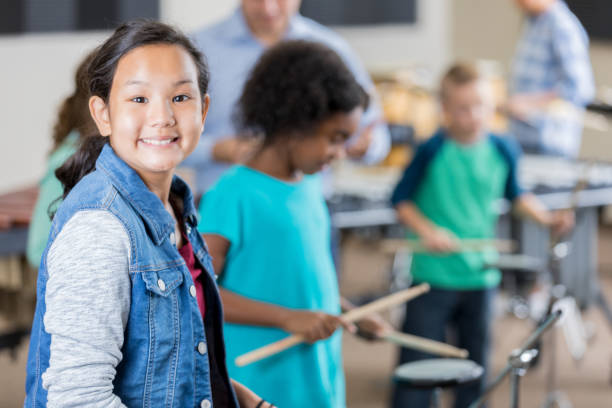 istock Confident schoolgirl playing drums during music class 904190830