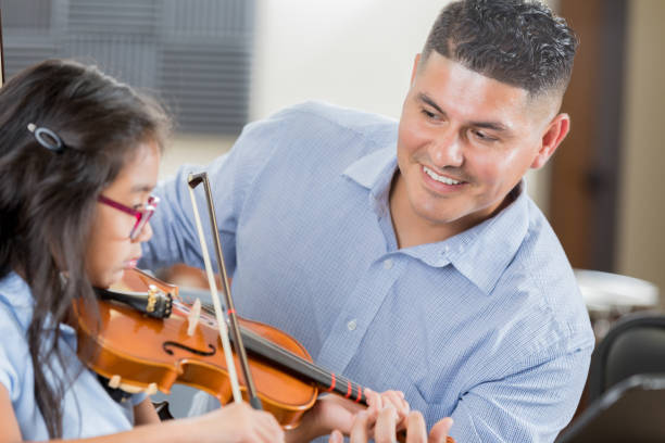 istock Cheerful music teacher helps student with violin lessons 904190860