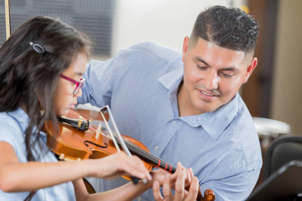 уверенный учитель музыки помогает девочке со скрипкой - latin american and hispanic ethnicity child violin music стоковые фото и изображения