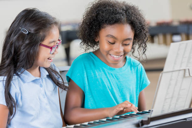 istock Girls play keyboard together during music class 904190910
