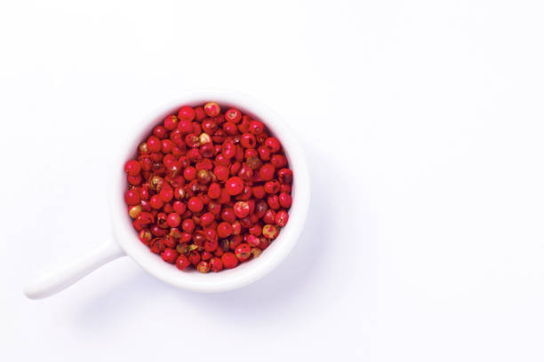 Organic Pink Peppercorn in white ceramic cup on white background with copy space