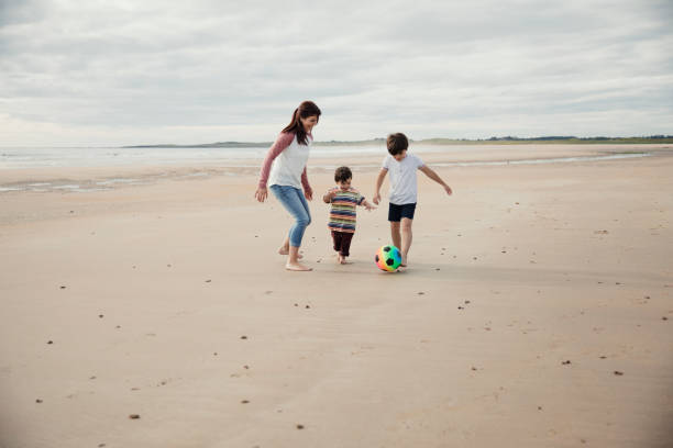 istock Mother and Children Playing On The Beach with a Ball 904199264