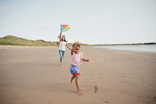 A mother and daughter playing on the beach with a kite in Northumberland
