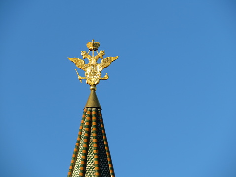Golden double-headed eagle on the top of the tower in Moscow. The national emblem of Russia on the background of blue sky