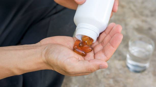 mężczyźni biorą kapsułkę oleju słonecznikowego. - lecithin capsule brown vitamin pill zdjęcia i obrazy z banku zdjęć