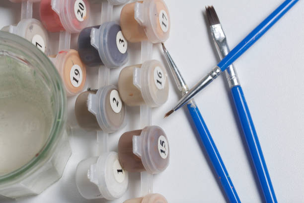 istock Paints for drawing by numbers. Several containers with paint are open. There are tassels, a sheet of paper nearby. 904230752