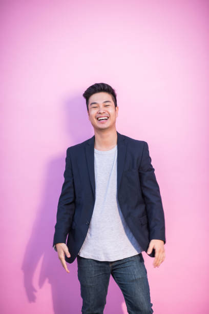 Happy Asian young man goofing around​ outdoors against building wall