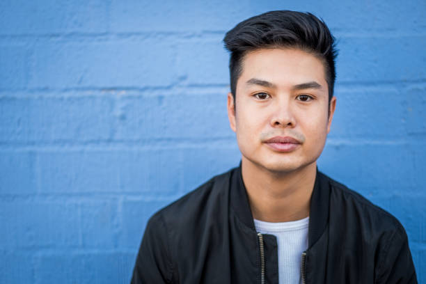 Asian young man standing outdoors against building wall