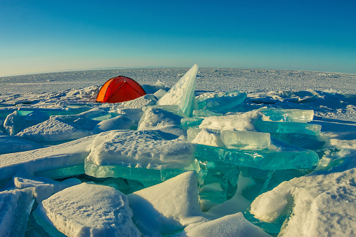 Orange tent stands alone among the ice hummocks and Lake Baikal.