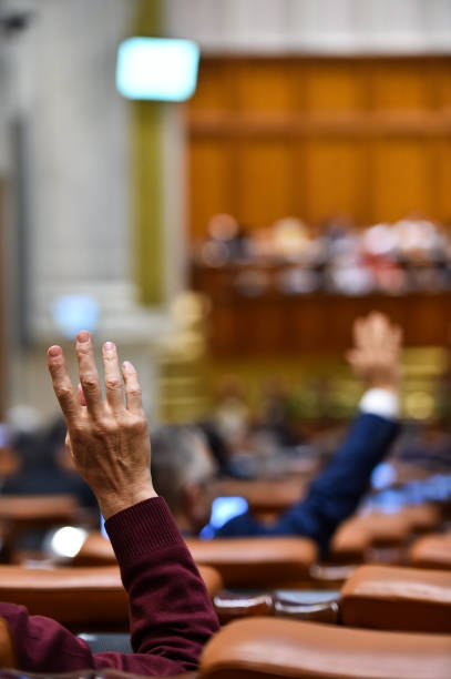 istock Hand of a man raised in the air during a voting procedure 904234330