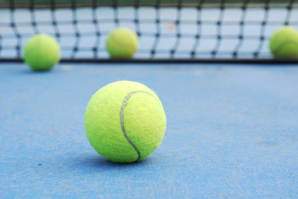 istock tennis balls on court with net 904235106