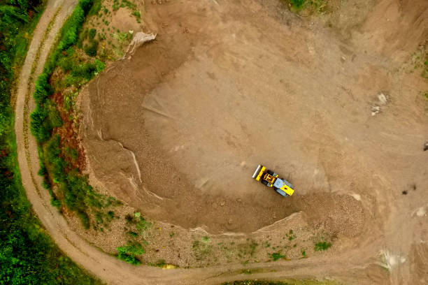 Aerial view of a spoil heap with a sickle-shaped geometry and a wheel loader Aerial view of a spoil heap with a sickle-shaped geometry and a wheel loader, made by drone slag heap stock pictures, royalty-free photos & images