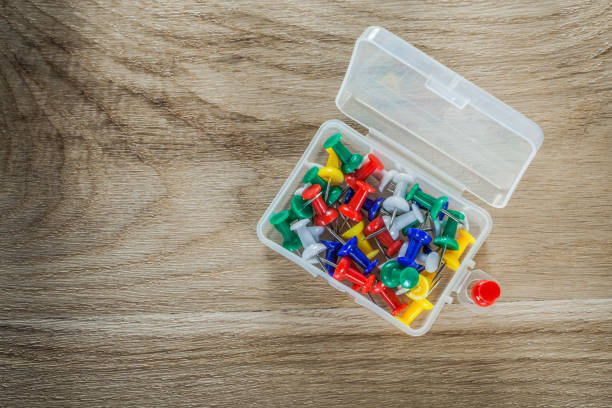 istock Set of drawing pins in plastic box on wooden board 904239364