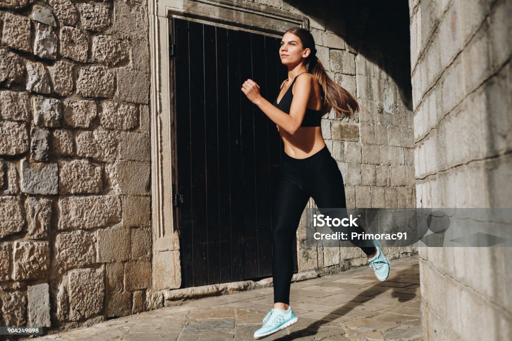 Run for the life Beautiful fit girl running through the city streets Jogging Pants Stock Photo