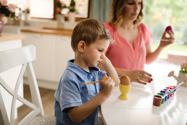 istock Mother and her son having fun decorate eggs 904250214