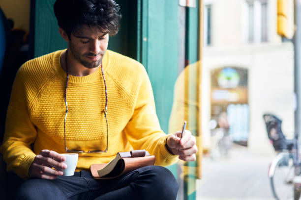 istock Talented male journalist thinking over creation book review while getting warm enjoying aroma coffee working in comfortable cafe interior getting inspiration sitting near window with notebook 904254764