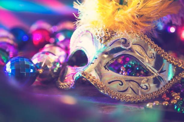 Mardi Gras, Rio carnival mask and colorful decorations. Mardi Gras or Rio Carnival mask and colorful carnival decorations.  Scene includes: gold feathered mask, colored party lights, and beads.  Objects lie on wooden table.  No people. bead photos stock pictures, royalty-free photos & images