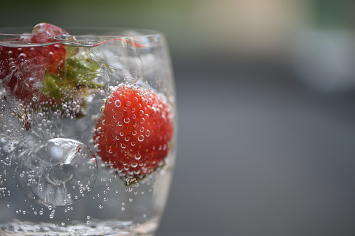 Freshly washed strawberries are placed in crystal glassware with a plaid napkin in the background.