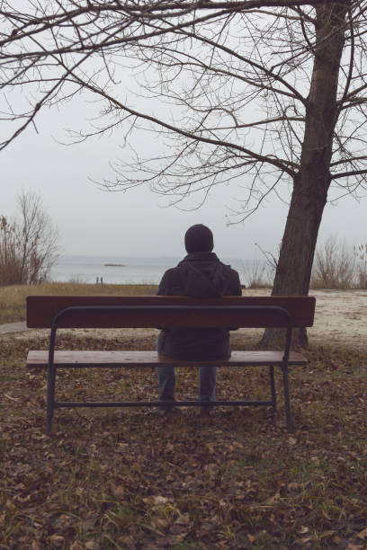 istock The man is sitting on the bench and looking at the river. 904261060