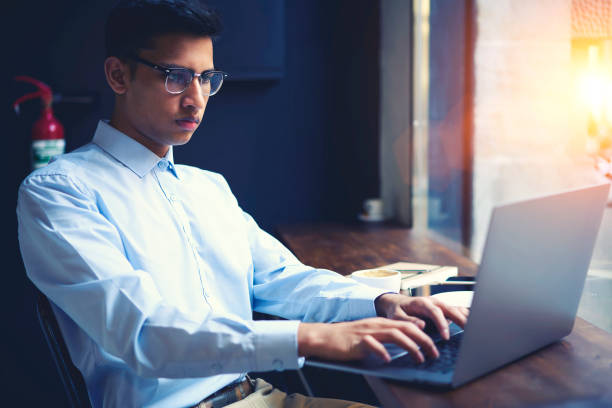 istock Concentrated handsome well-dressed male international student typing on laptop computer text of creative report for homework using information from web sources while sitting in coffeeshop with wifi 904265820