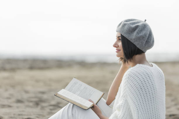 istock Young woman reading book on beach 904269600