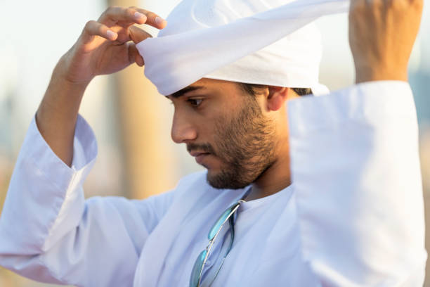 Handsome Arab wearing headscarf Young Emirati man at an outdoor location adjusting his headscarf arabian sunglasses stock pictures, royalty-free photos & images