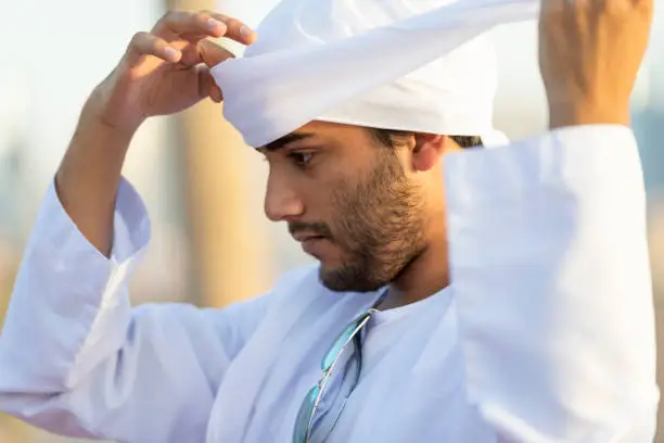 Young Emirati man at an outdoor location adjusting his headscarf