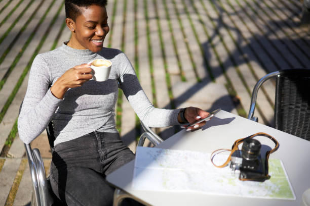 fille de joyeux hipster femme séduisante recréant assis en terrasse de café avec une tasse de messages textos café via touristique cellulaire, jeune femme, planification de visite de la ville en utilisant application sur smartphone - lundi noir chinois photos et images de collection