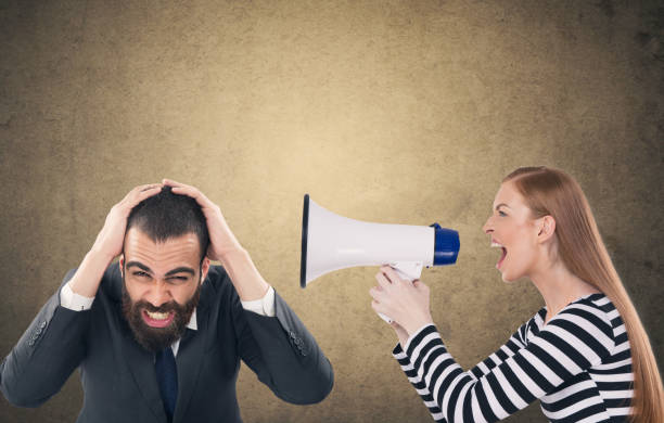 istock Woman screaming through megaphone at scared businessman 904275342