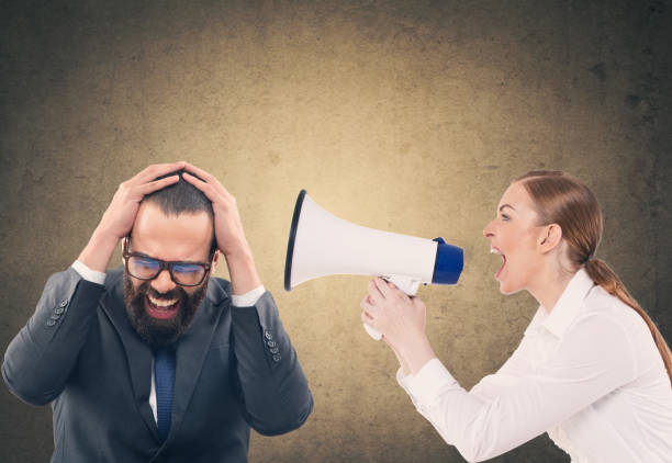 istock Woman screaming through megaphone at scared businessman 904275372