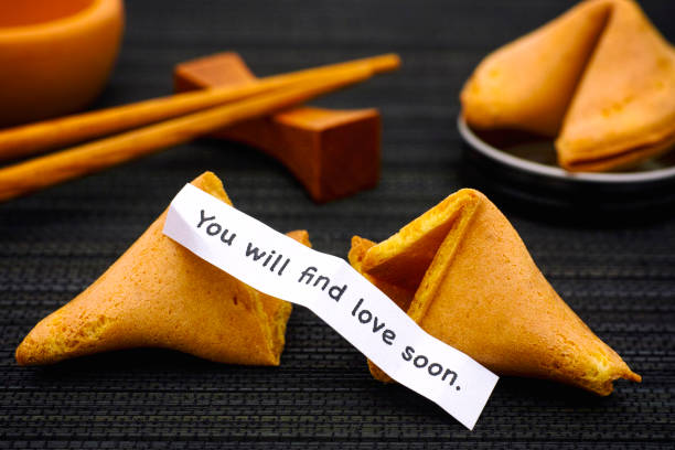 istock Paper strip with phrase You will find love soon. from fortune cookie, another cookie and chopsticks on black napkin background. 904281364