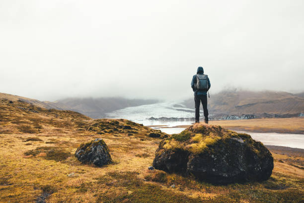 Backpacker standing on the rock and enjoying the view on Vatnajokull glacier in Iceland.
