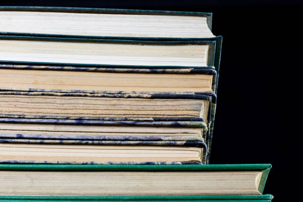 istock The spines of old books lying on the stack. Books stacked on an old table. Black background. 904312252