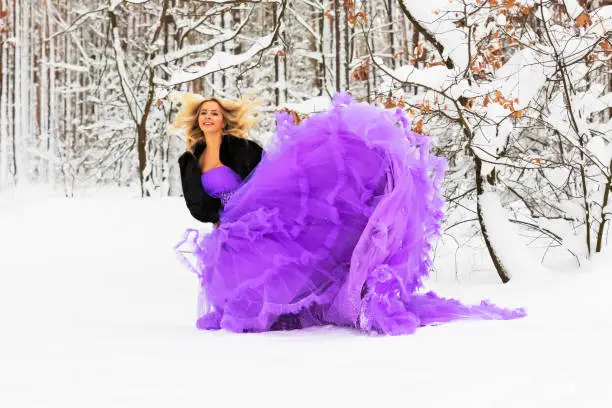 Photo of Young woman in a long dress in winter forest